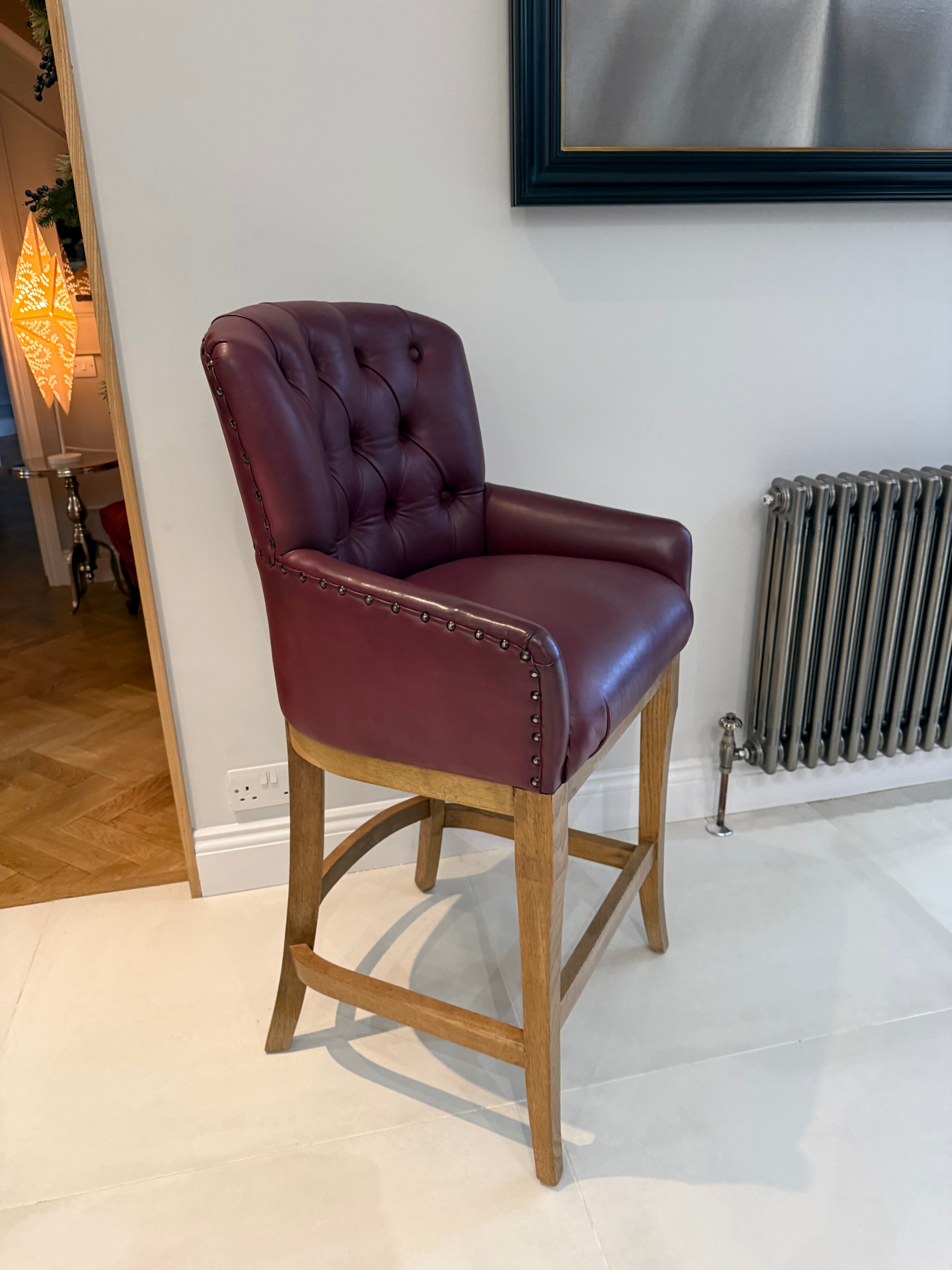 Red leather bar stool with oak frame against a white wall.