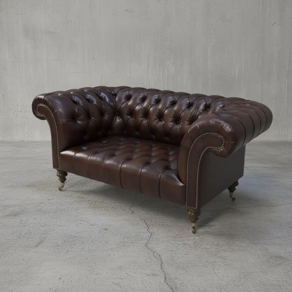 A brown leather Chesterfield sofa with tufted backrest and splayed arms, resting on turned wooden legs.