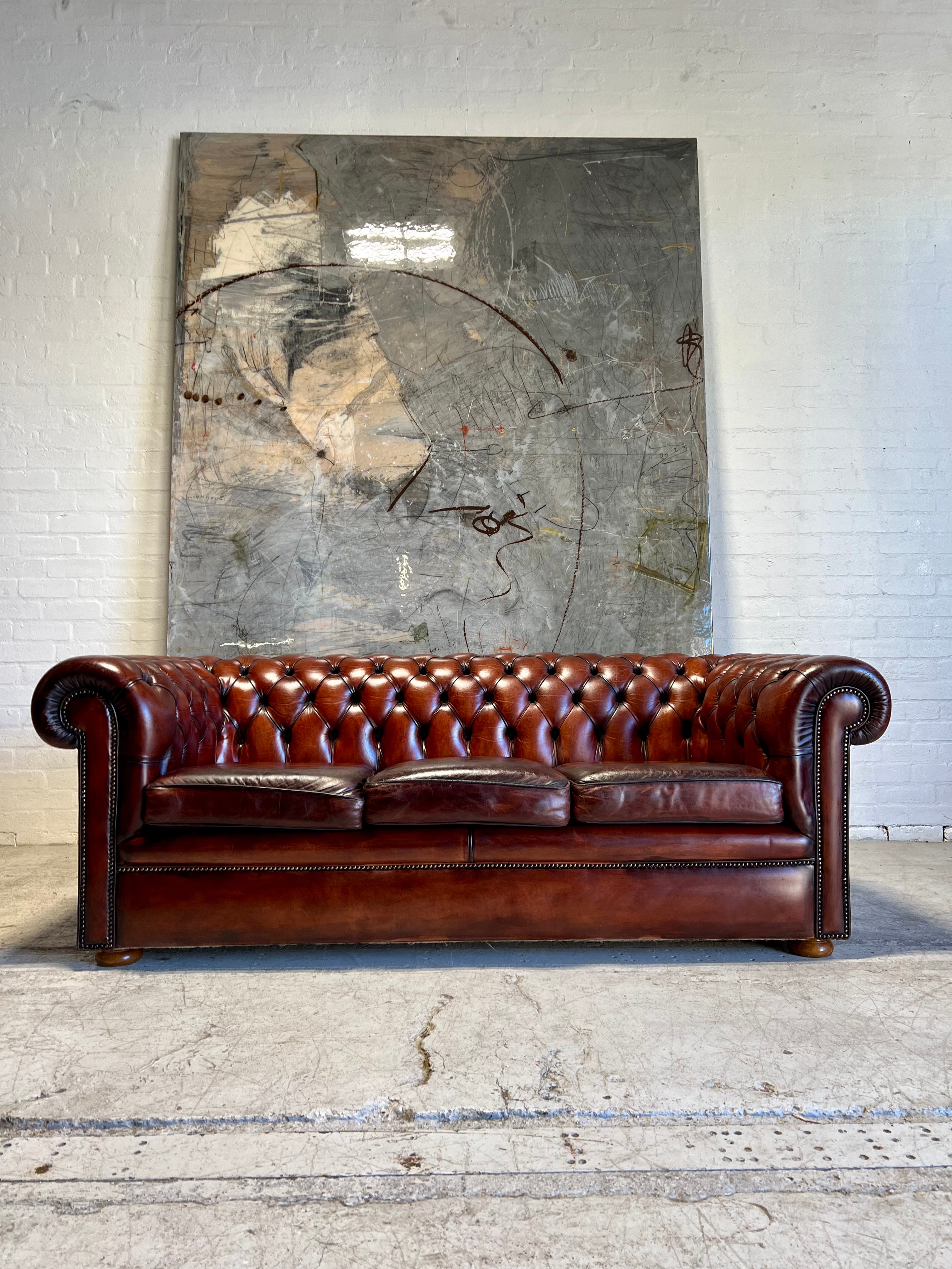 An Amazing Matching Pair of MidC Hand Dyed Leather Chesterfield Sofas Finished in A Cognac Wine